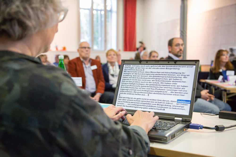 Eine Protokollantin notiert sich die Gespräche. Menschen mit Hörschädigungen beim Bürgerdialog 