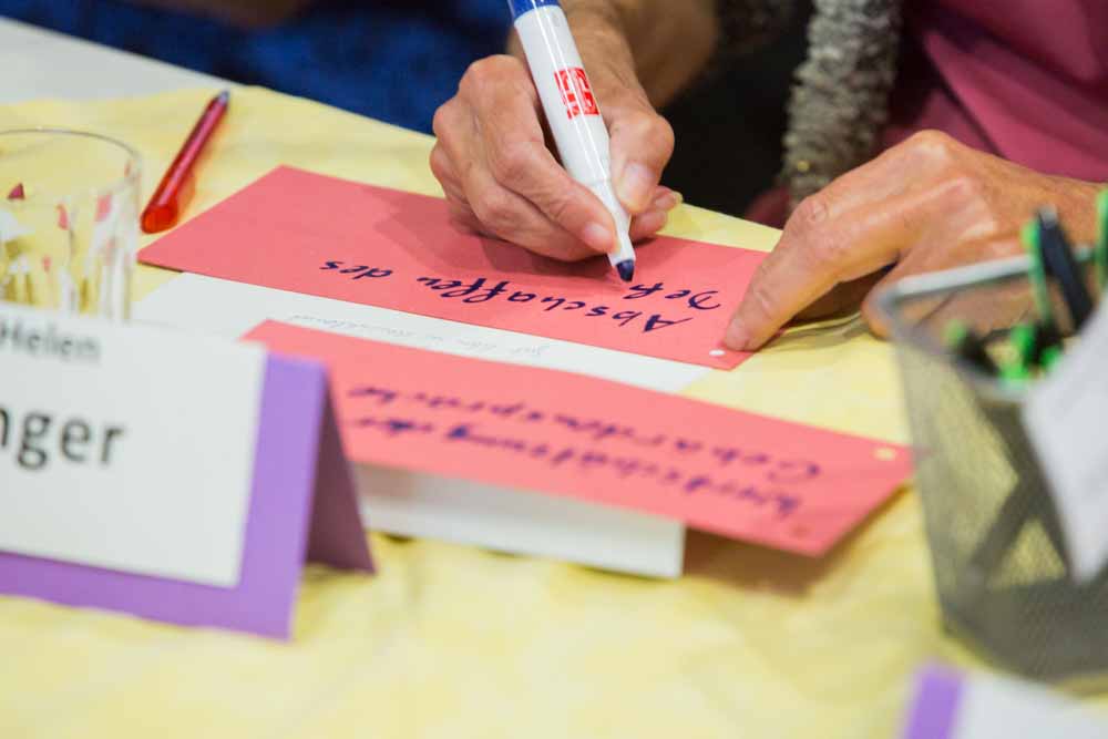 A participant takes notes. People with hearing impairments discuss participation and accessibility at the Citizens' Dialogue 