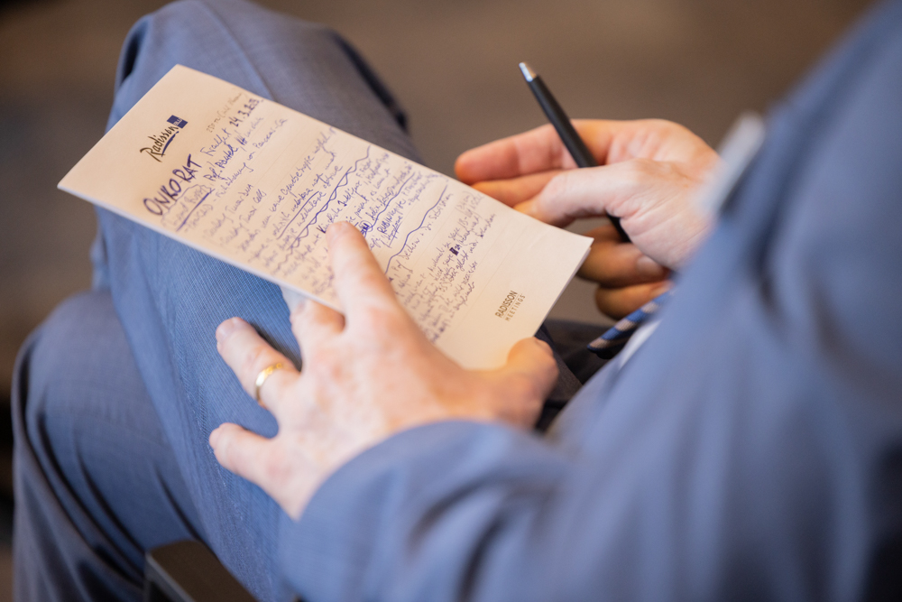 Ein Teilnehmer macht sich Notizen während einer Veranstaltung des OnkoRats 2023 von Iomedico. Fotografische Begleitung von Eventfotografie Martin Leissl