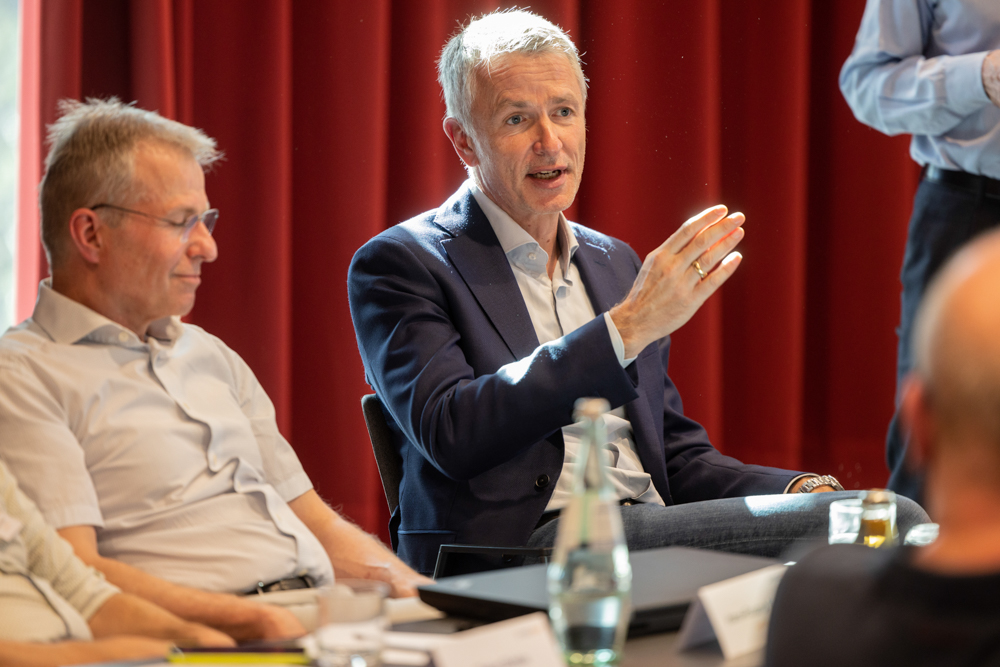 Teilnehmer des OnkoRats 2023 von Iomedico tauschen lebhaft Ideen während eines Seminars aus. Eventfotograf Martin Leissl dokumentiert das Geschehen.