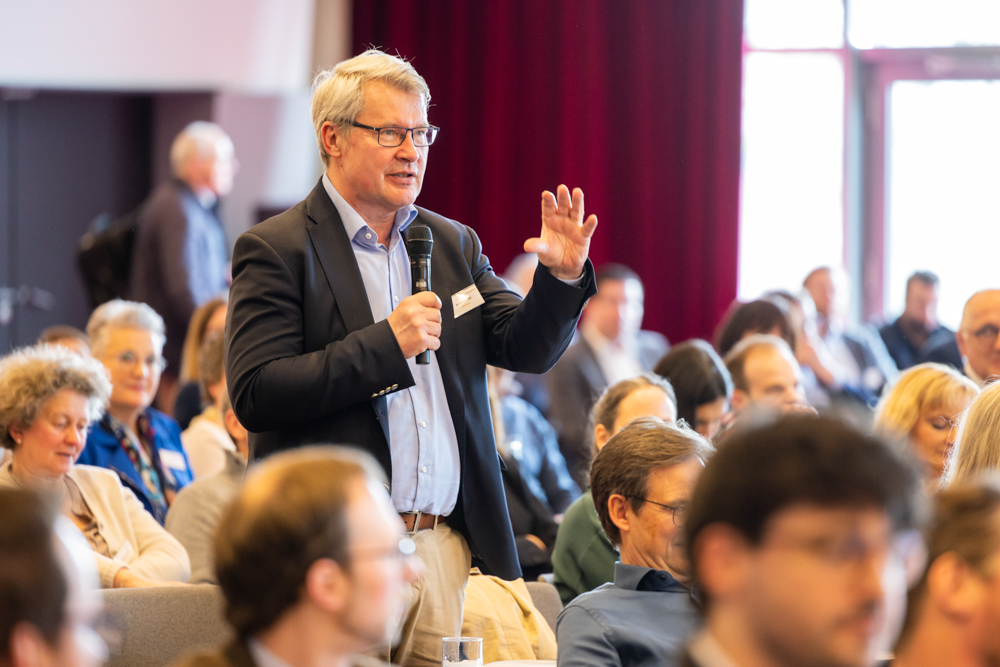 Ein Teilnehmer des OnkoRats 2023 von Iomedico meldet sich während des Plenums zu Wort . Martin Leissl Eventfotograf Frankfurt dokumentiert das Geschehen.
