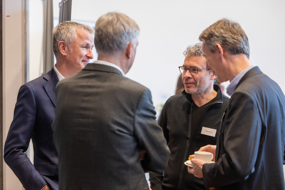 Teilnehmer des OnkoRats 2023 von Iomedico tauschen lebhaft Ideen während einer Pause aus. Martin Leissl Eventfotografie dokumentiert das Geschehen.
