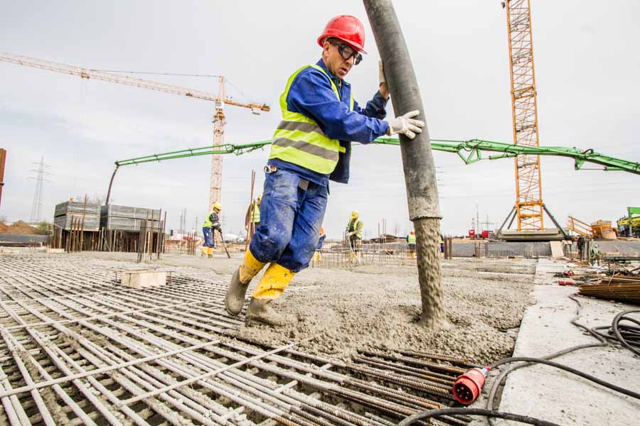 Photo report on the new construction of the Clariant Innovation Center. A construction worker applies concrete to a steel frame.