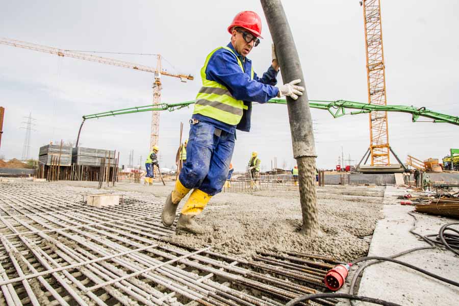 Fotoreportage über den Neubau des Clariant Innovation Centers. Ein Bauarbeiter trägt Beton auf ein Stahlgerüst auf.