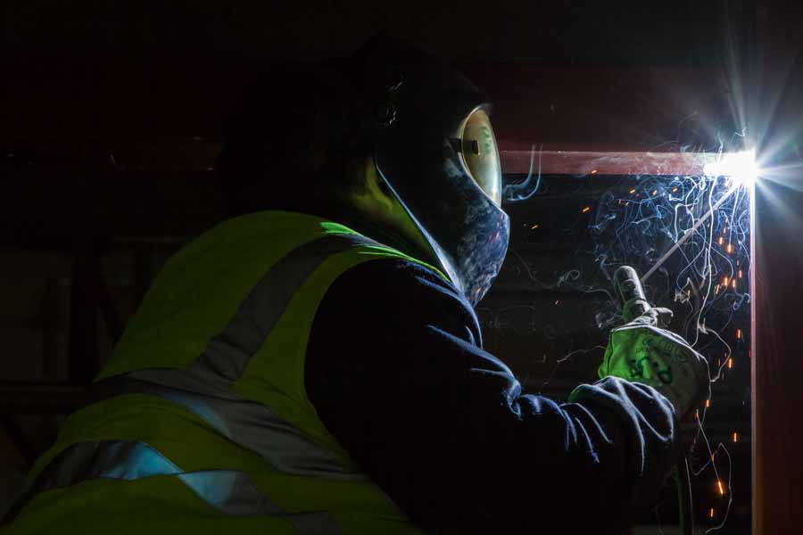 A craftsman welds steel beams in the shell of the new Clariant research center