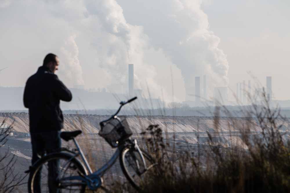 A cyclist stands beside his bicycle beside the Garzweiler open cast lignite mine, operated by RWE AG, in Garzweiler, Germany