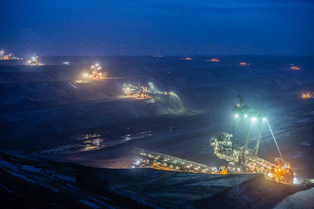 Lights illuminate giant excavators as they operate at dusk at the Garzweiler open cast lignite mine, operated by RWE AG, in Garzweiler, Germany.